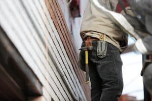 Builder in a toolbelt working beside a house, shoulders down