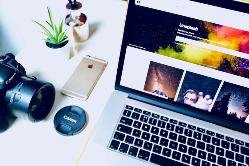 Bright, modern design studio desk with a laptop, DSLR camera and small succulent, laptop screen open to a stock photo search